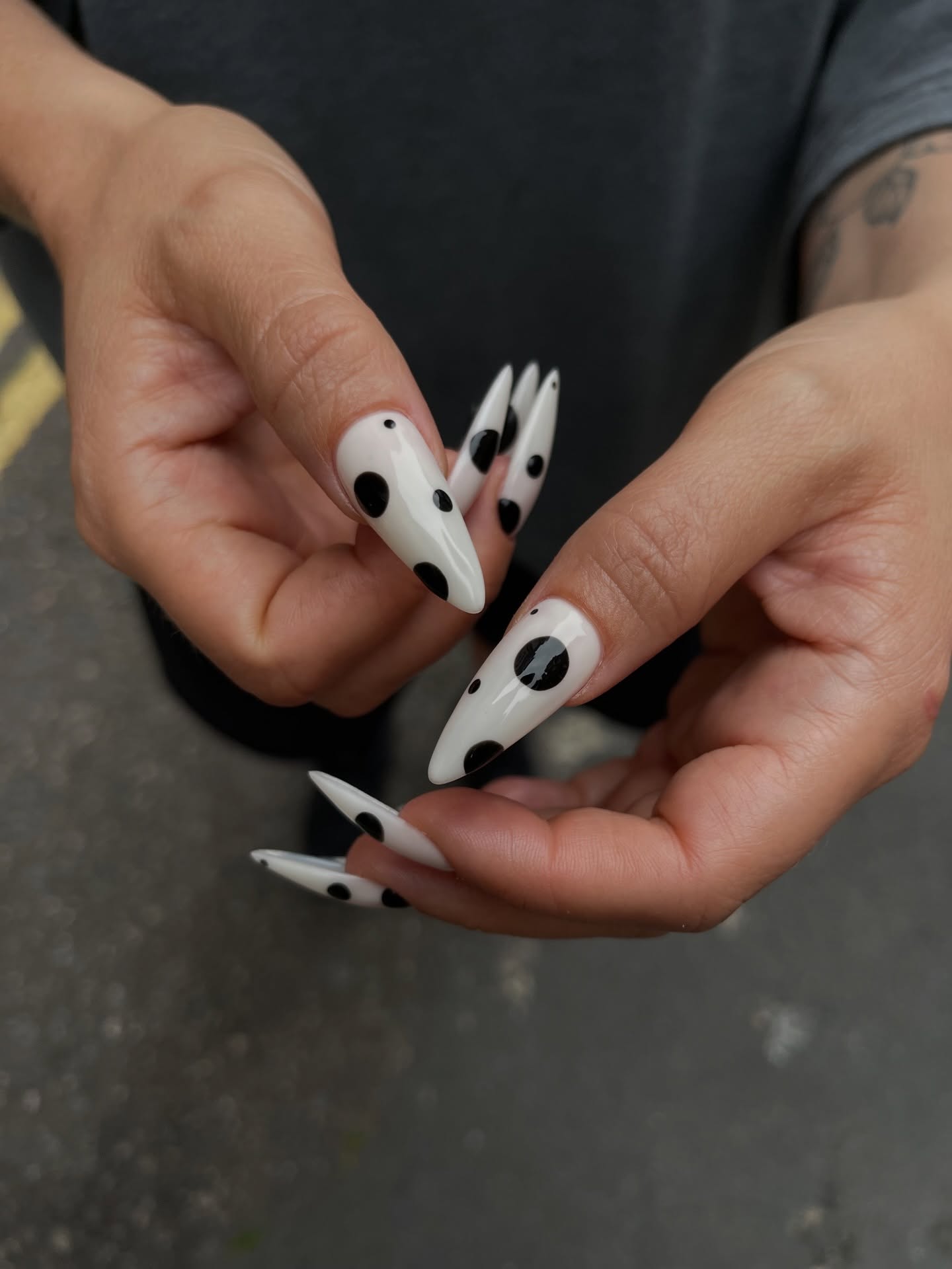 black cow-print spots scattered across extra-long pointed white nails