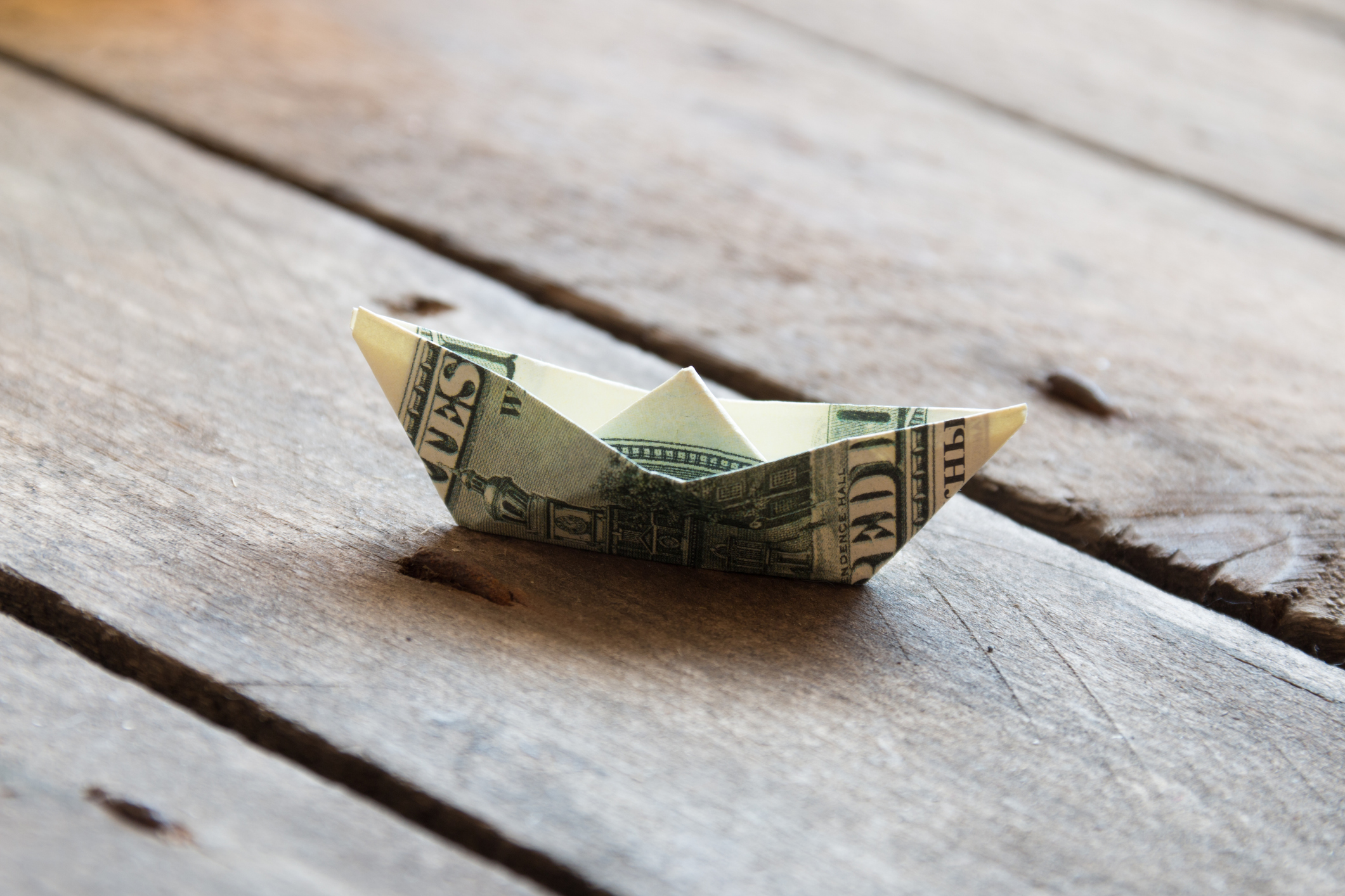 ship made out of money on wooden floorboards