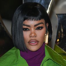 a black woman wears a black bob haircut and dark eye makeup while posing for paparazzi at an event