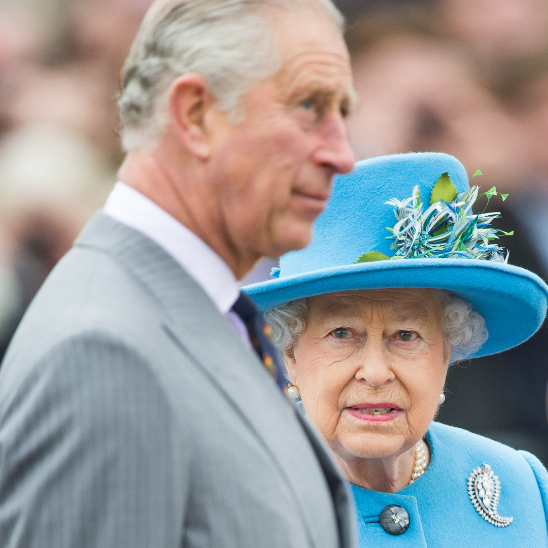 King Charles is in side profile and has white gray hair while wearing a gray pinstripe suit while his mother, Queen Elizabeth II, wears a turquoise blue coat dress and matching hat