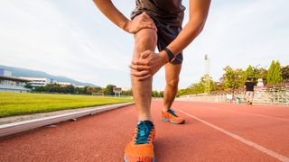 a photo of a runner holding his injured knee