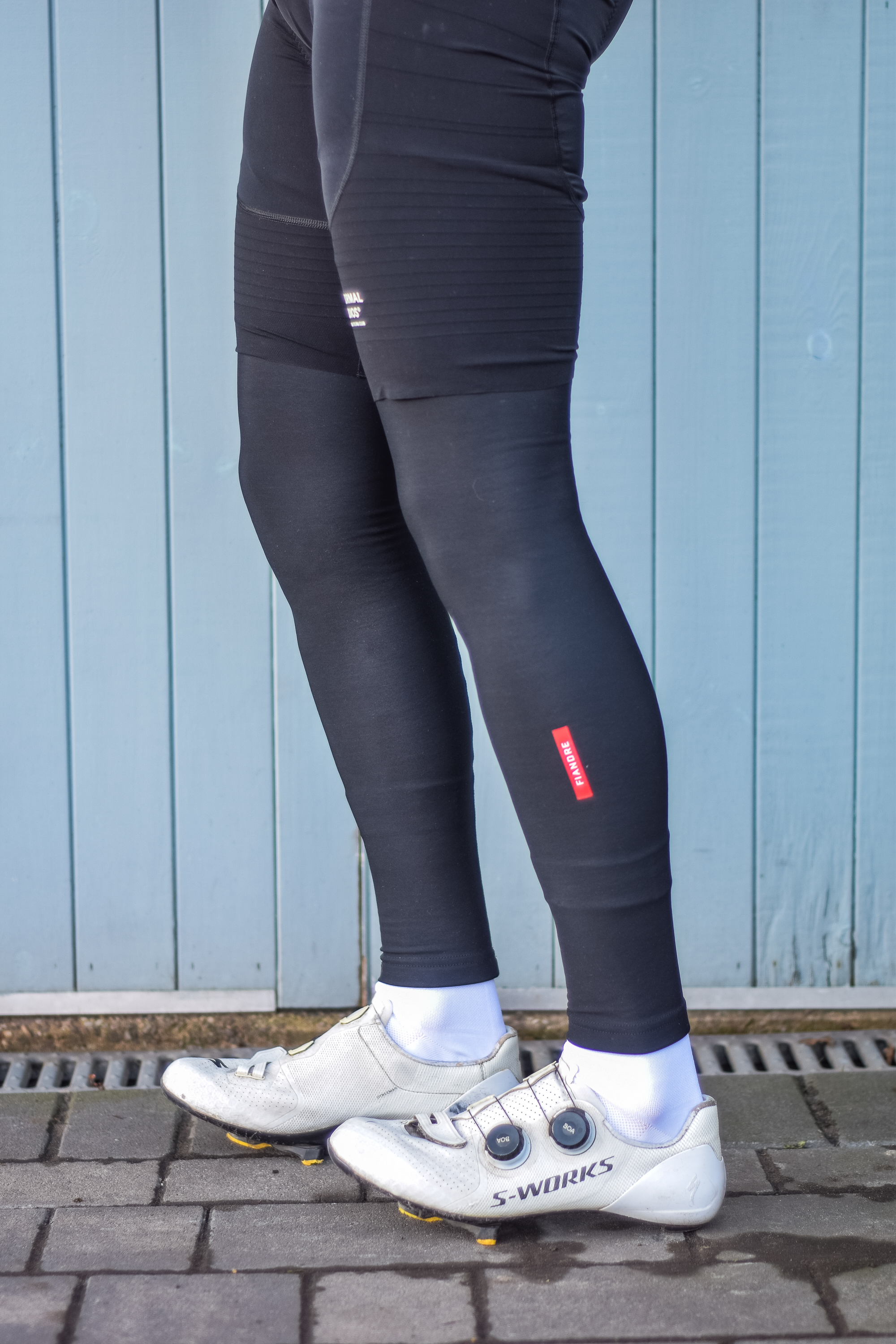 A man wearing cycling shorts and leg warmers in front of a blue door 