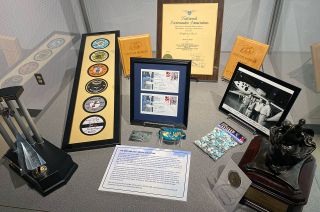 a table packed with mementos on display from the Melvill collection including flight test patches, award trophies and commemorative M&Ms.