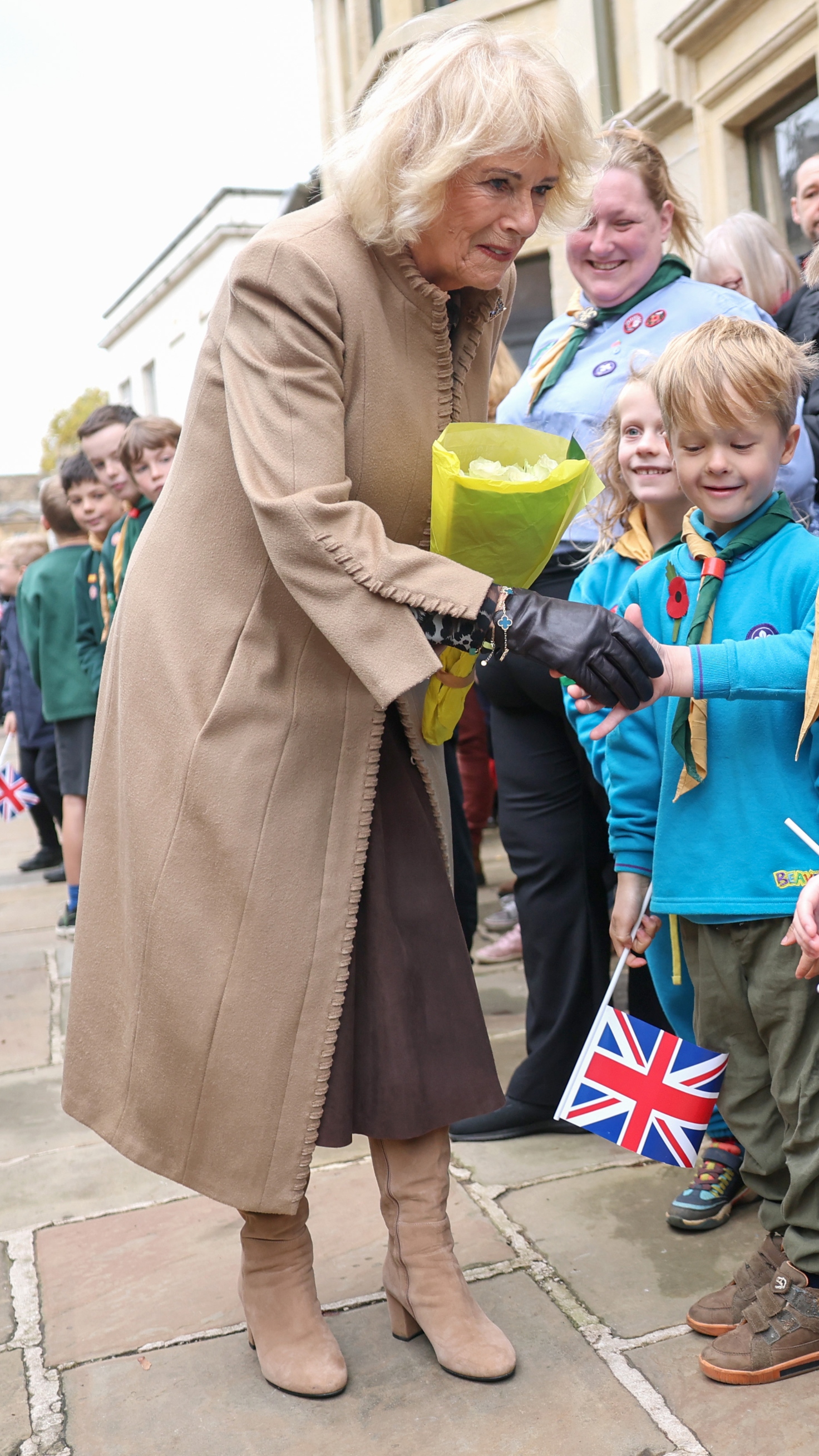 Queen Camilla shakes hands with a young well-wisher during her visit to The Poppy Project on October 28, 2025