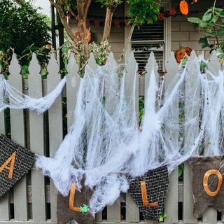 A fence decorated for Halloween with plastic cobwebs