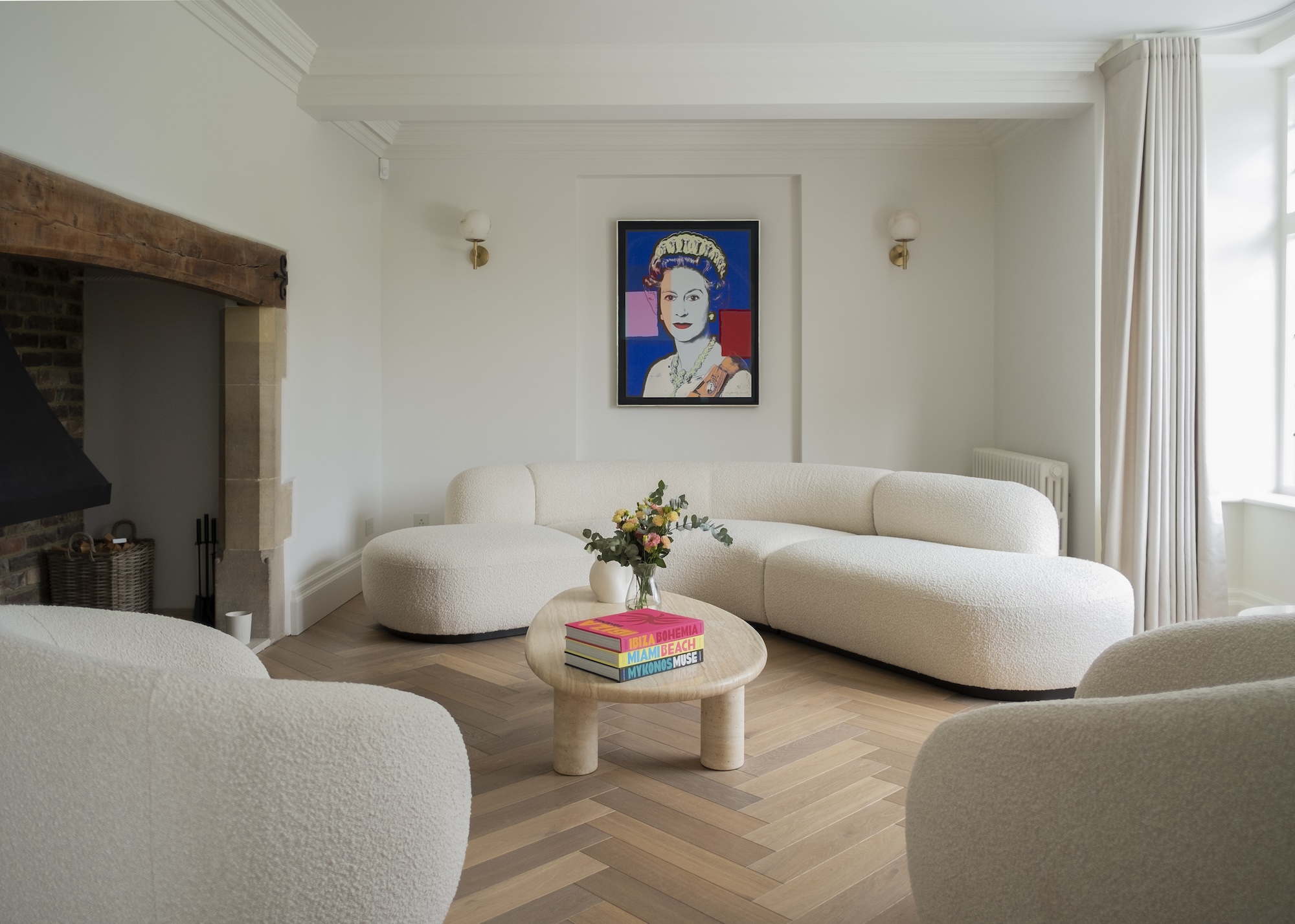 a neutral living room showing a large curved corner sofa, two armchairs and a coffee table with herringbone wood plank floors