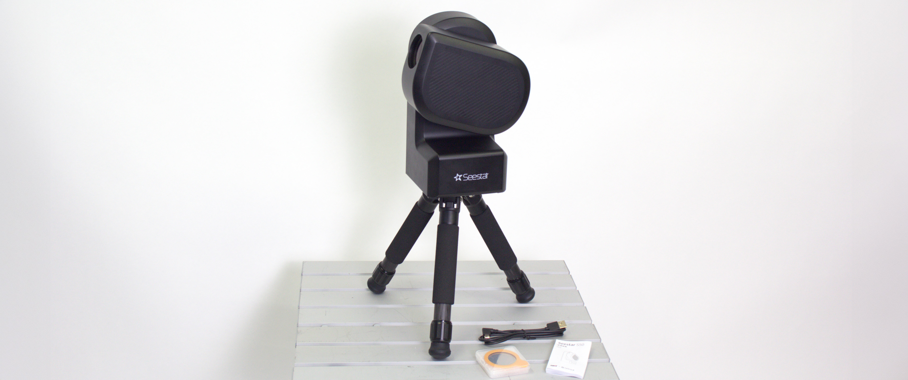 ZWO Seestar S50 on a table against a white wall