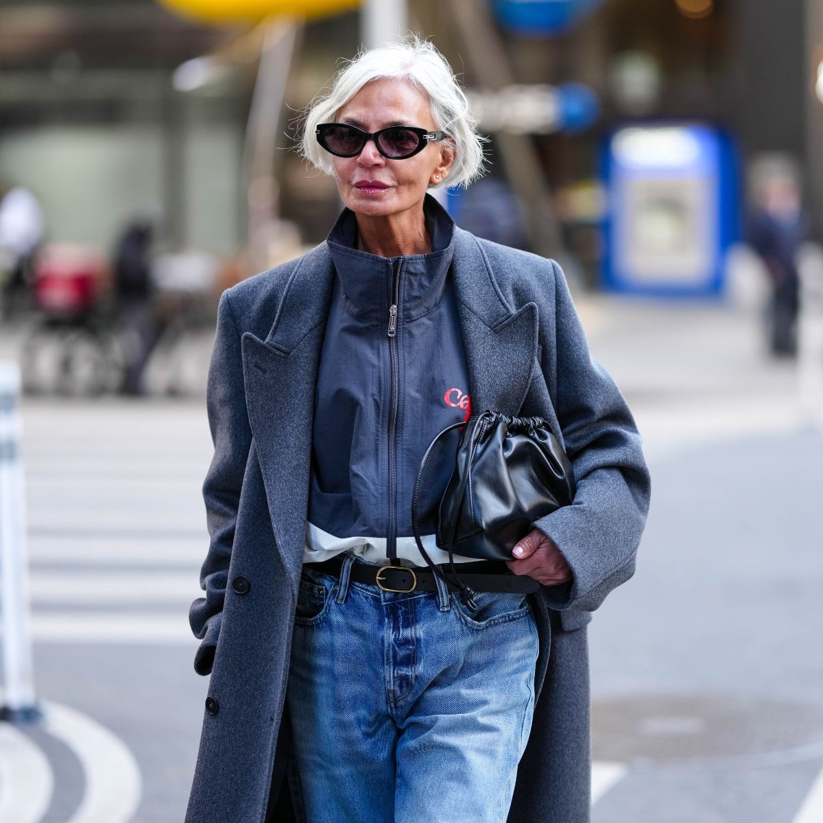 grece ghanem wears sunglasses a grey coat jeans and a black handbag