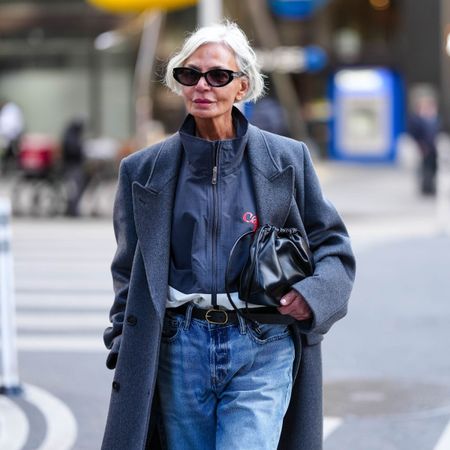 grece ghanem wears sunglasses a grey coat jeans and a black handbag
