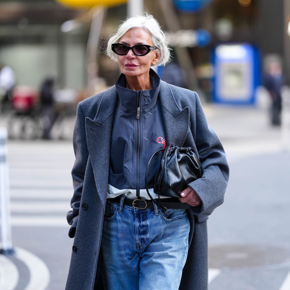 grece ghanem wears sunglasses a grey coat jeans and a black handbag