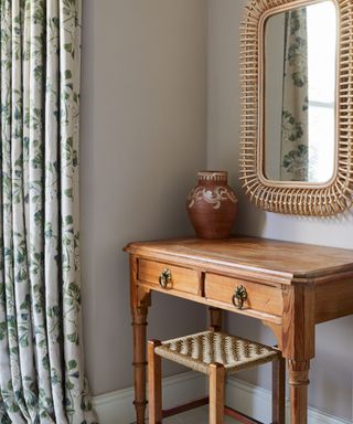 bedroom with a vintage dressing table, stool with rattan seat and a vintage rattan large mirror