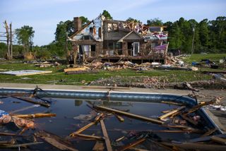 a photo of a destroyed house with debris floating in a pool in the foreground