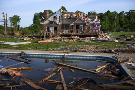 a photo of a destroyed house with debris floating in a pool in the foreground
