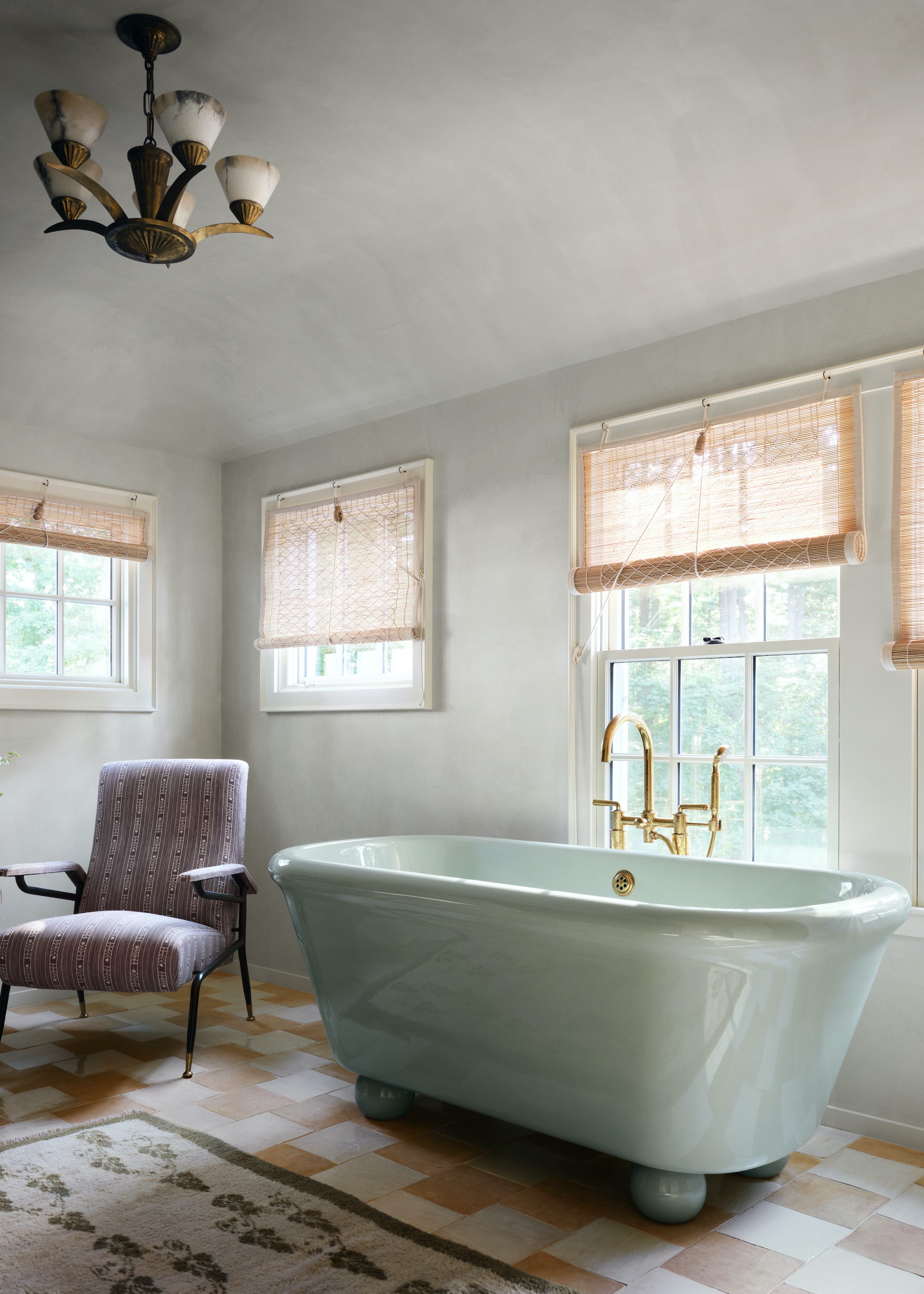 bathroom with zellige tiles and mint green bath in the space. There is also a chair beside the bath tub