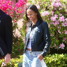 zoe salda&ntilde;a wearing a black leather jacket, blue jeans, and leopard print flats 