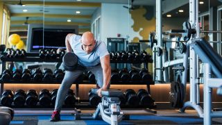 Man performs one-arm dumbbell row in gym