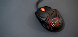 En svart gaming-mus av typen Cooler Master MM720 på et mørkt underlag.