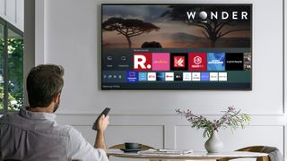 Mann med fjernkontroll ser på en Samsung-TV-