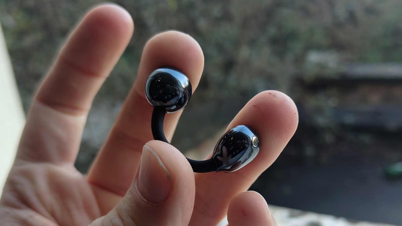 The Huawei FreeClip 2 in a man's hand, being stretched.