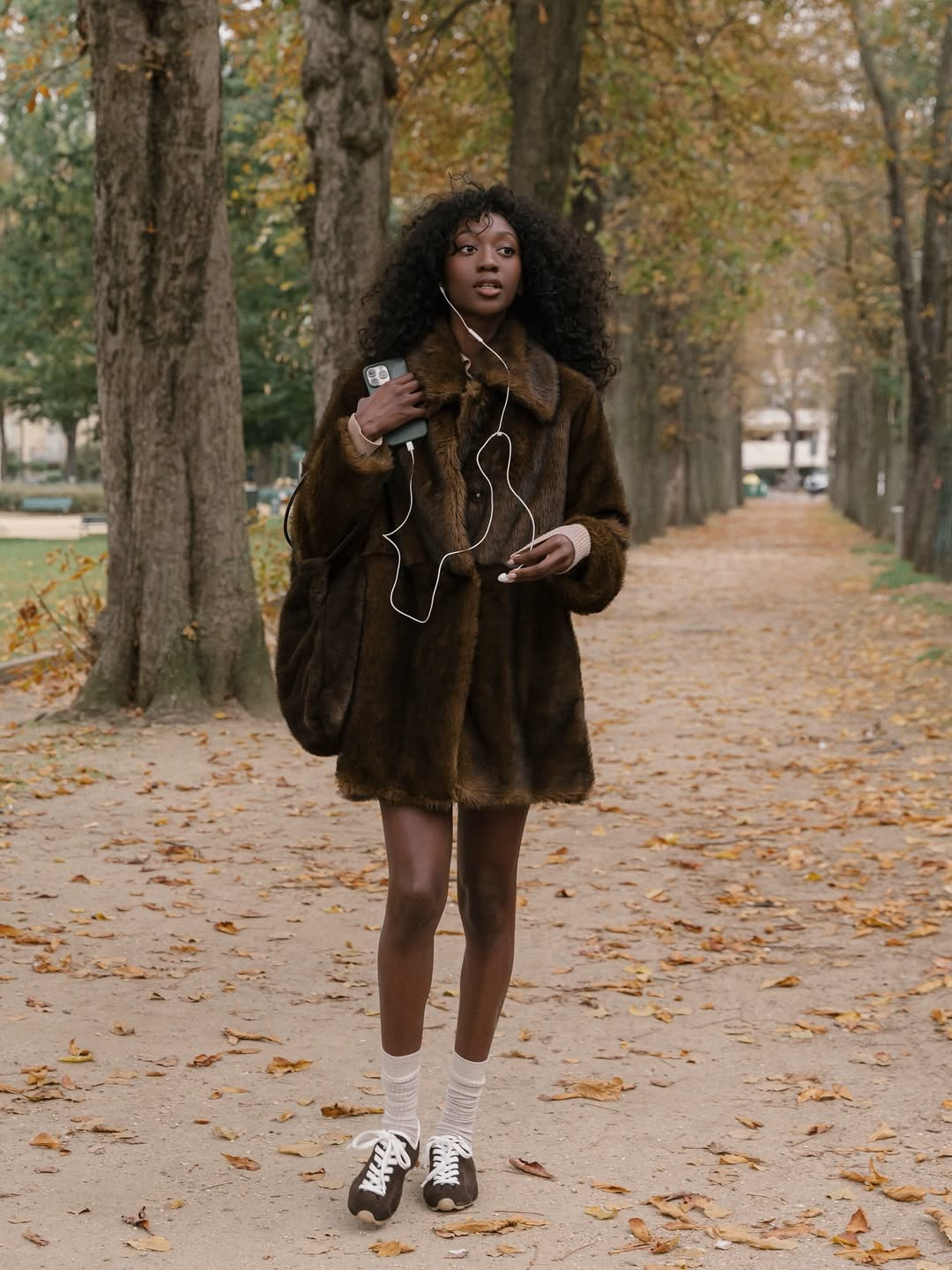 A woman in a brown faux-fur coat and sneakers