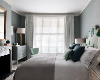 Gray apartment bedroom ideas with a patterned headboard and sheer drapes.