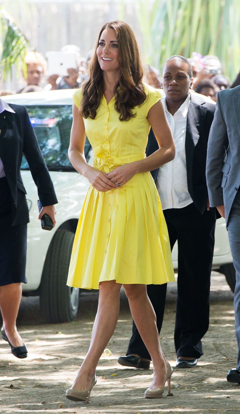 For a casual outing to the village of Honiara on Guadalcanal Island, she looks classic in a bright yellow Jaeger shirtdress and her famous nude L.K. Bennett pumps.