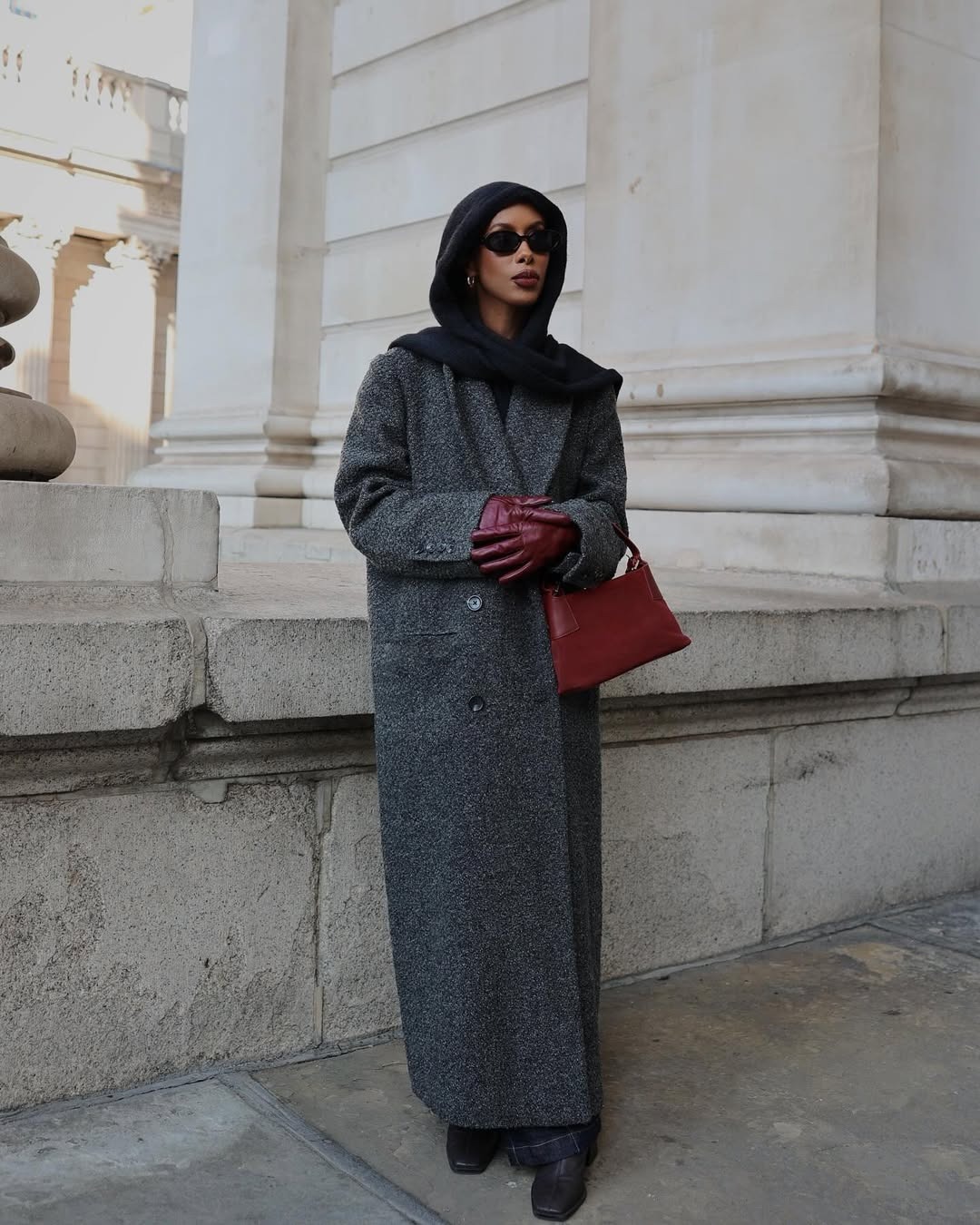 Content creator Basma in a textured floor-length coat, burgundy gloves, and red handbag.