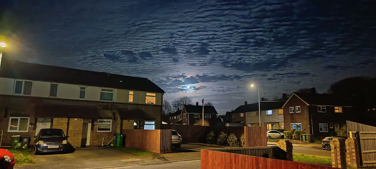 A night shot of the moon and sky above a cityscape