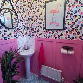 Colourful bathroom with pink and multi coloured patterned walls, sink and mirror