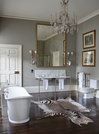 grey bathroom with a freestanding bath, chandelier and double sink with a marble countertop
