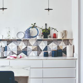 A white kitchen with a patterned tiled splashback