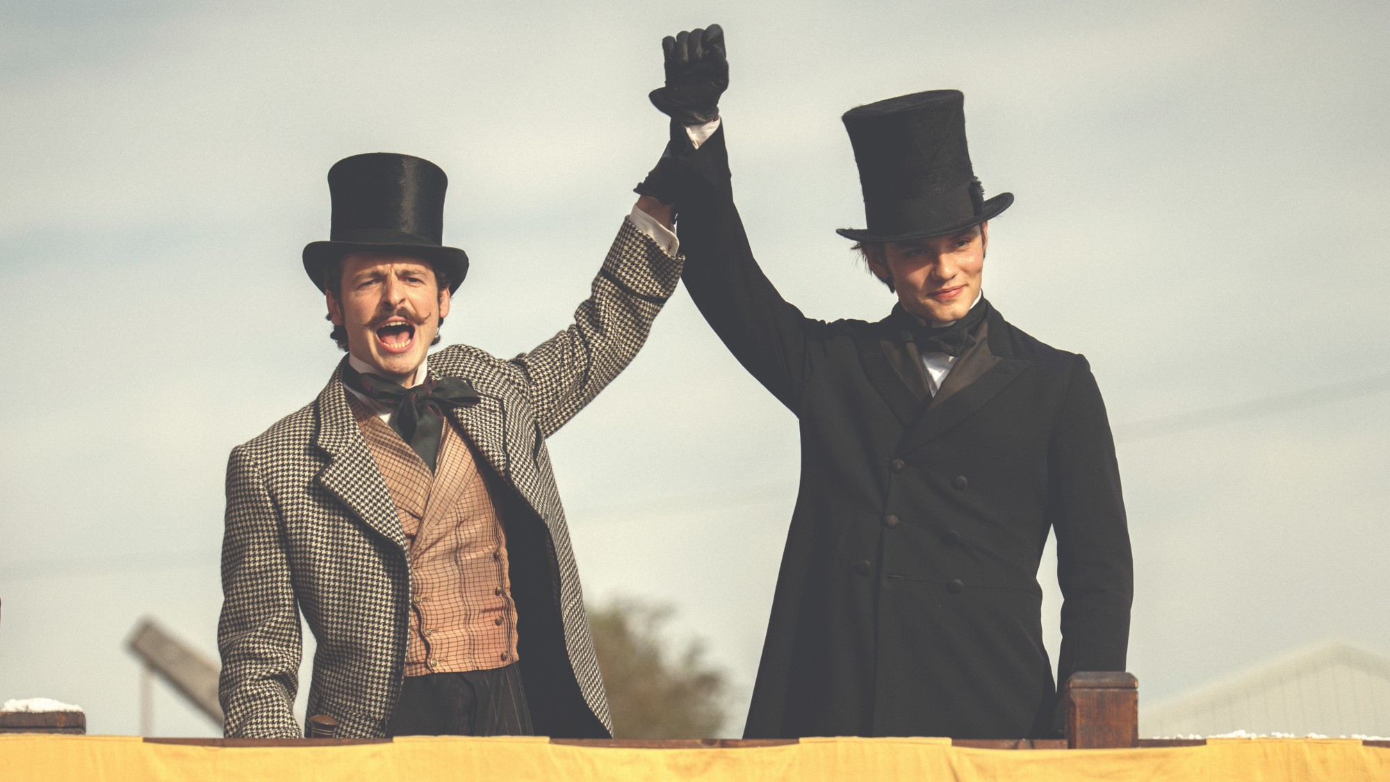 Two brothers of the Guinness family raise their arms