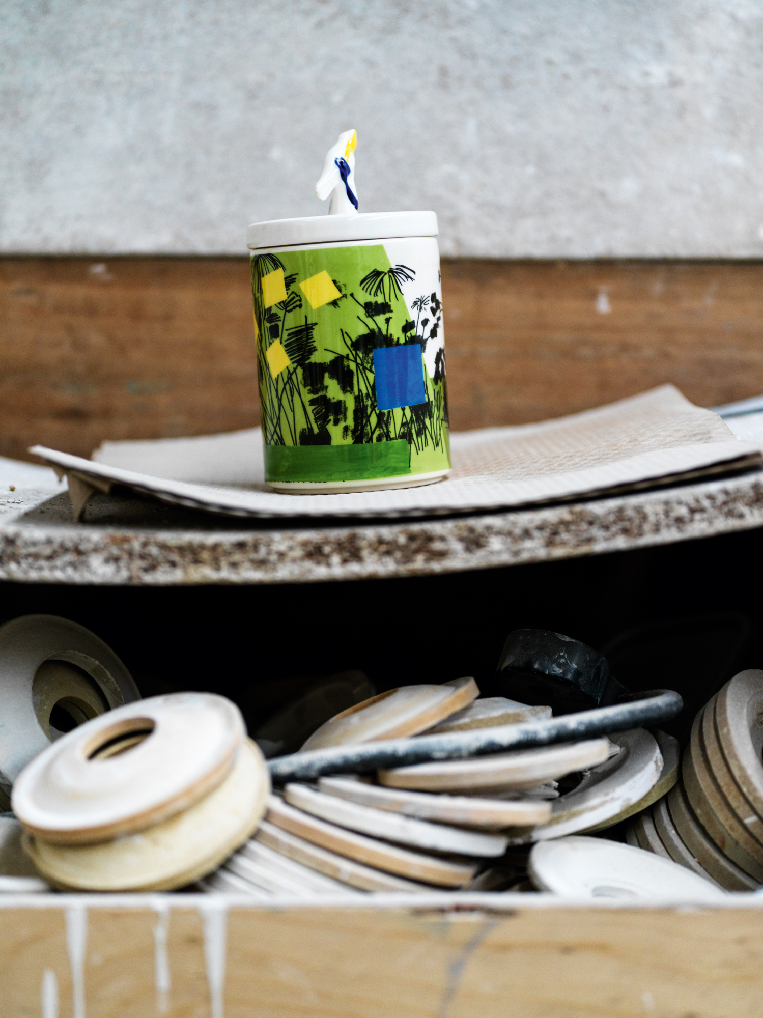 A green, blue and yellow ceramic vessel with a bird