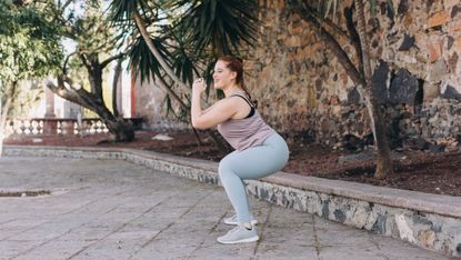 Woman performs squats outdoors