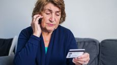 An older woman reads the numbers off a gift card to a caller.