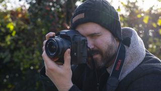 Photographer Dan Mold holding a Sigma DSLR outdoors with his eye to the viewfinder