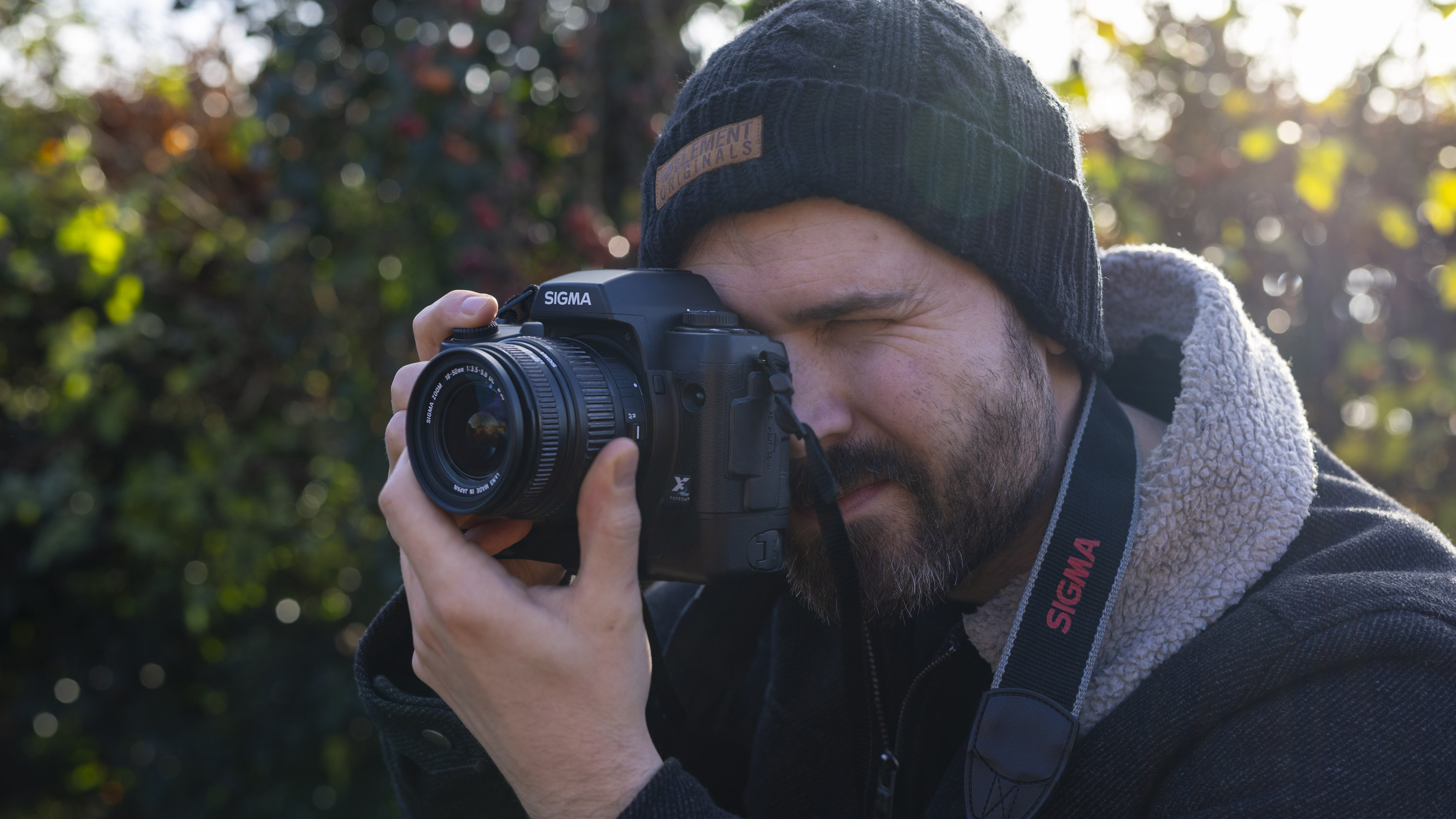 Photographer Dan Mold holding a Sigma DSLR outdoors with his eye to the viewfinder