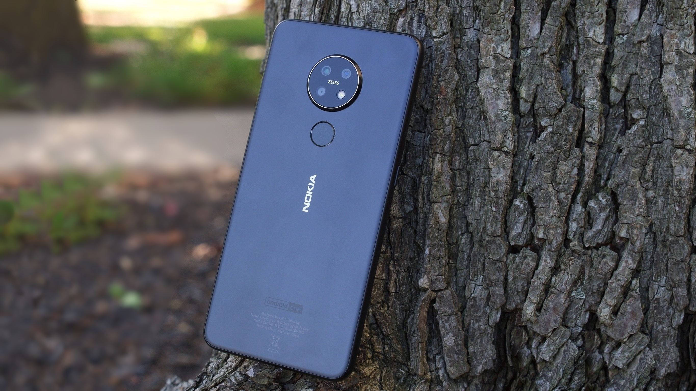 Nokia 7.2 standing upright leaning against a tree outdoors showing off its back