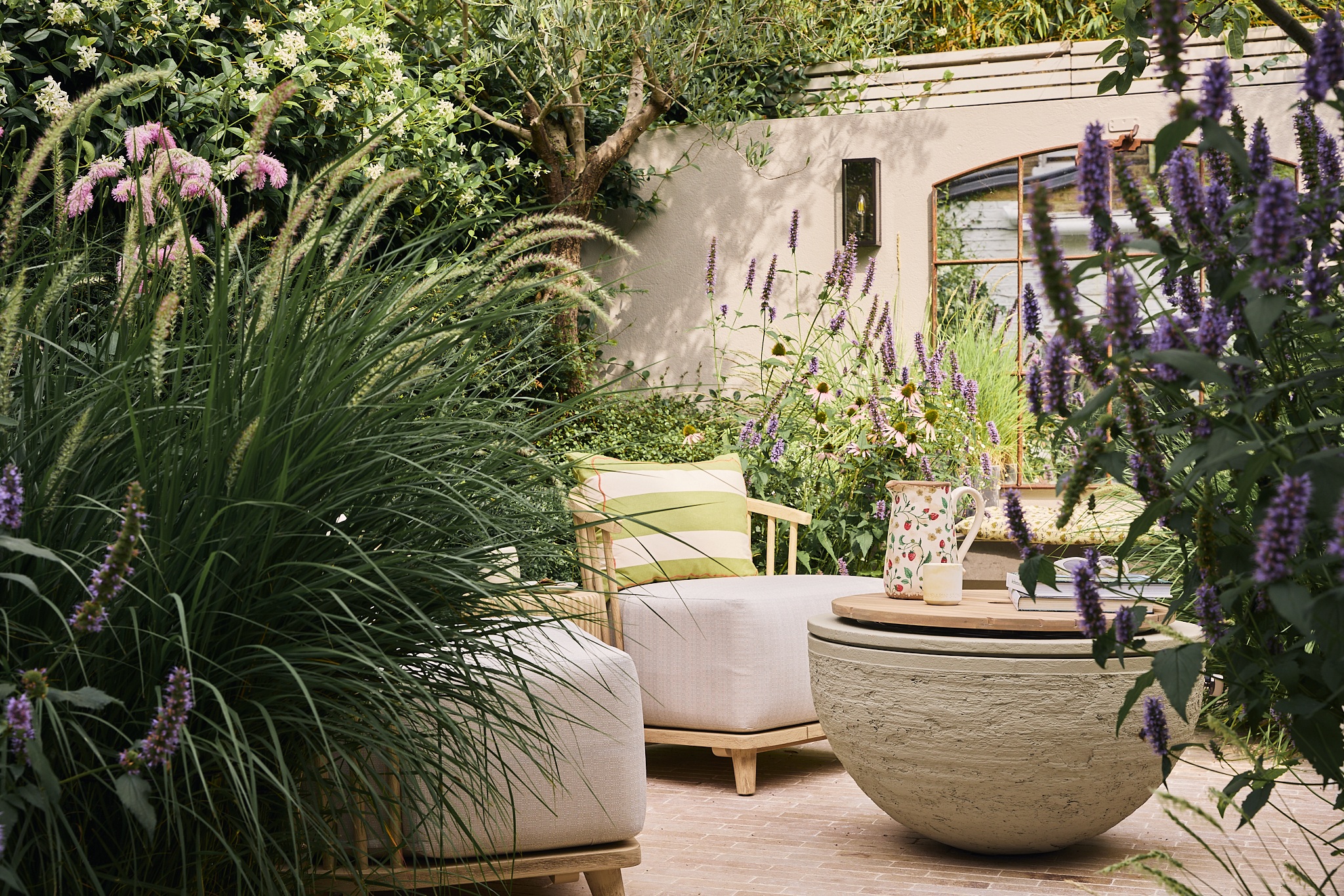a modern garden with lush planting, purple flowers, and sculptural landscaping