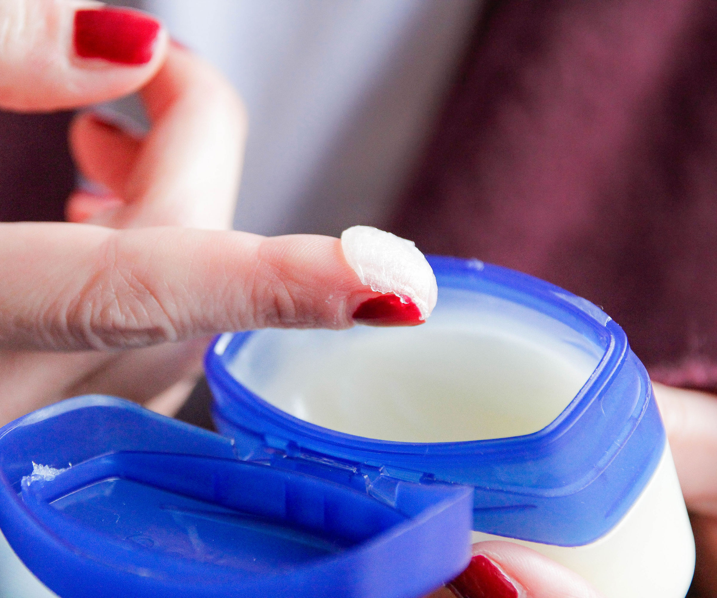 petroleum jelly being scooped out of plastic tub with finger