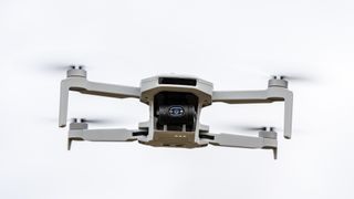 A white drone with black camera is in flight.