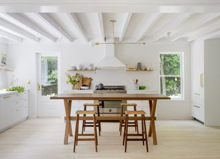 Large airy white kitchen with huge wooden trestle table in the centre