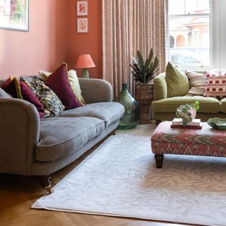 A terracotta orange-painted living room with a grey and green sofa decorated with multicoloured scatter cushions