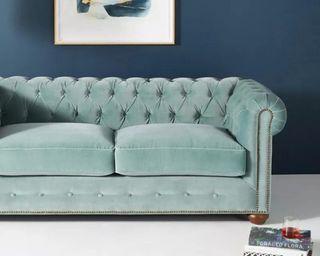Anthropologie green sofa with magazine beside
