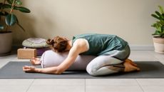 woman does a modified child's pose using a boulder 