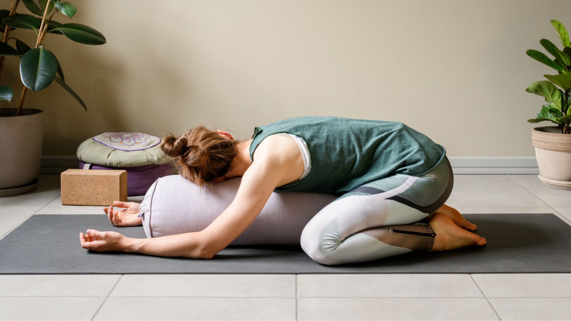 woman does a modified child's pose using a bolster