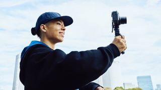 Sony ZV-1 II camera in a vlogger's hands with blue sky in the background