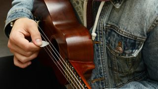 Man plays acoustic bass with a guitar pick