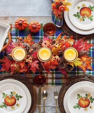 A thanksgiving themed candleholder with trio of wax candles on dining table with checkered tablecloth