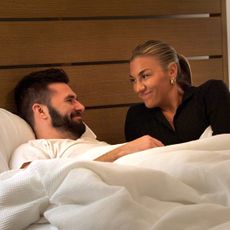 connor and bri lay in bed together and smile looking at one another in a still from love is blind season 10